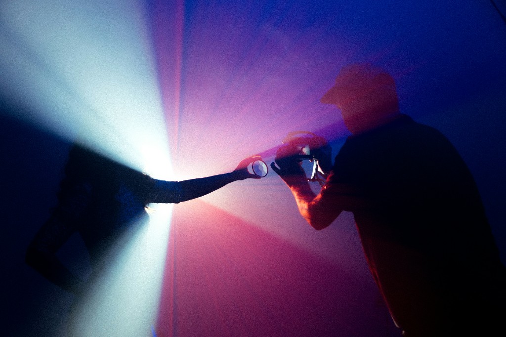 Créatifs en silhouette capturant la lumière : appareil photo et faisceaux colorés, ambiance artistique